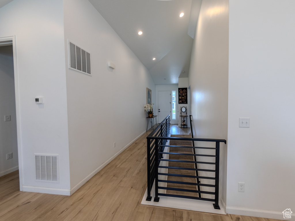 Hall with light wood-style flooring, recessed lighting, baseboards, an upstairs landing, and high vaulted ceiling