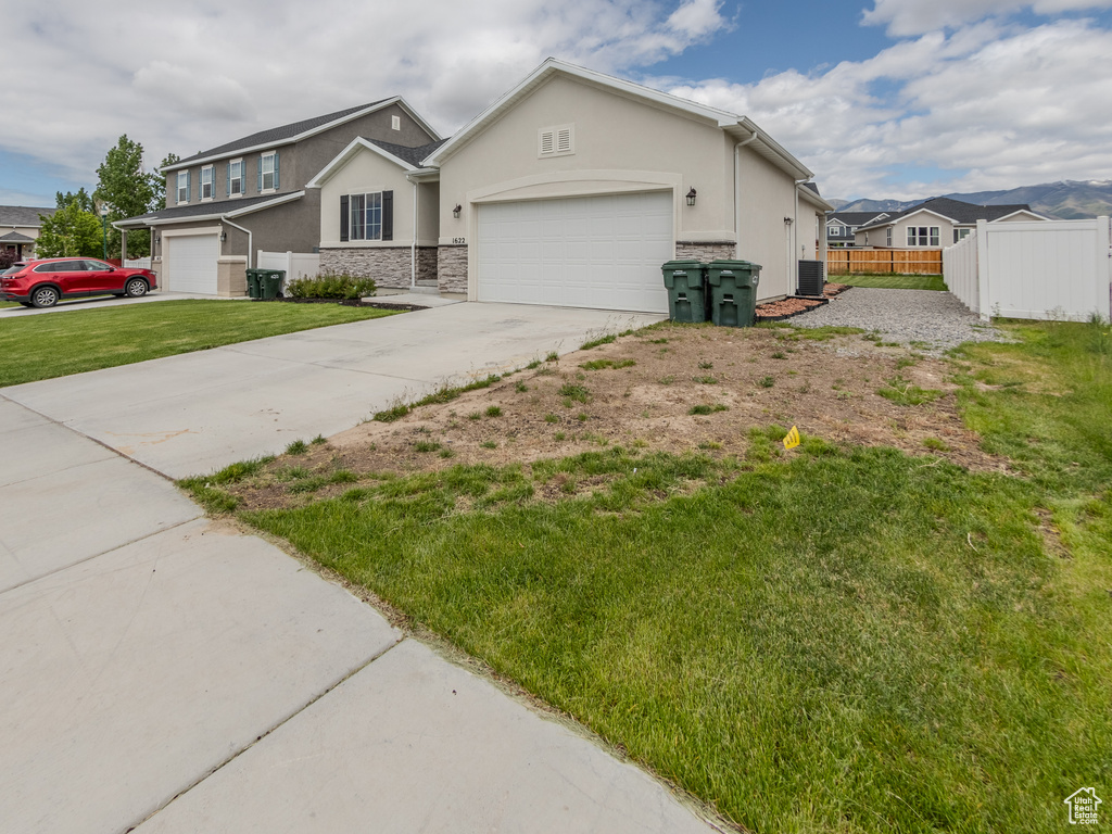 View of front of house with stucco siding, driveway, a garage, and stone siding