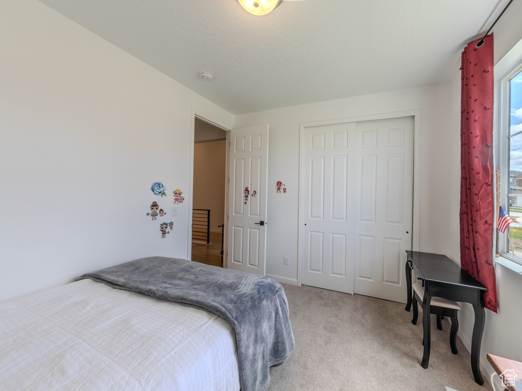 Bedroom featuring light carpet and a closet