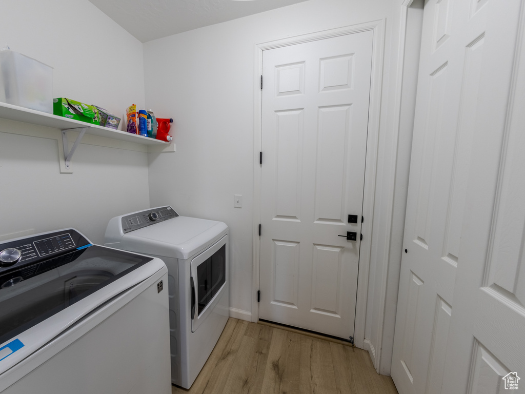 Laundry room with washing machine and clothes dryer and light wood-style floors