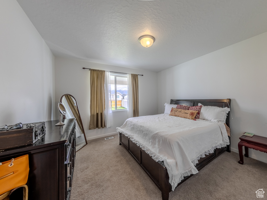 Bedroom with light colored carpet and baseboards