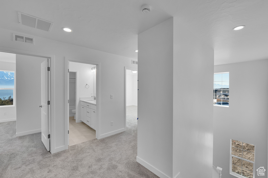 Hallway with light colored carpet, recessed lighting, baseboards, and a sink