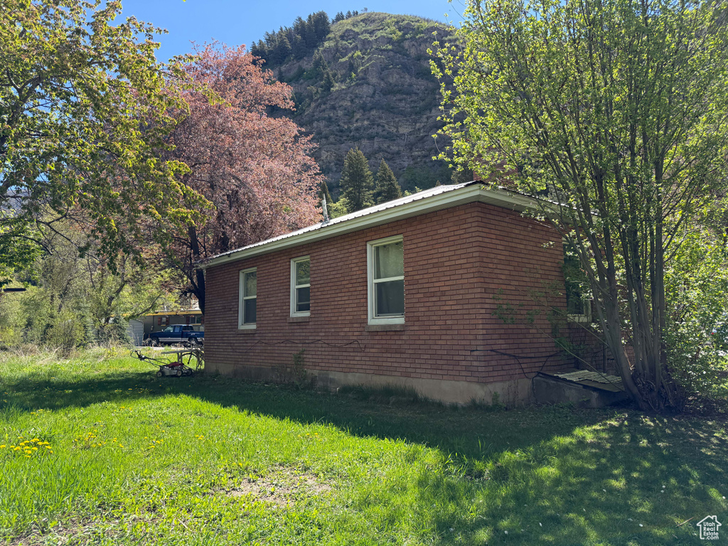 View of side of home with a lawn, a mountain view, and brick siding