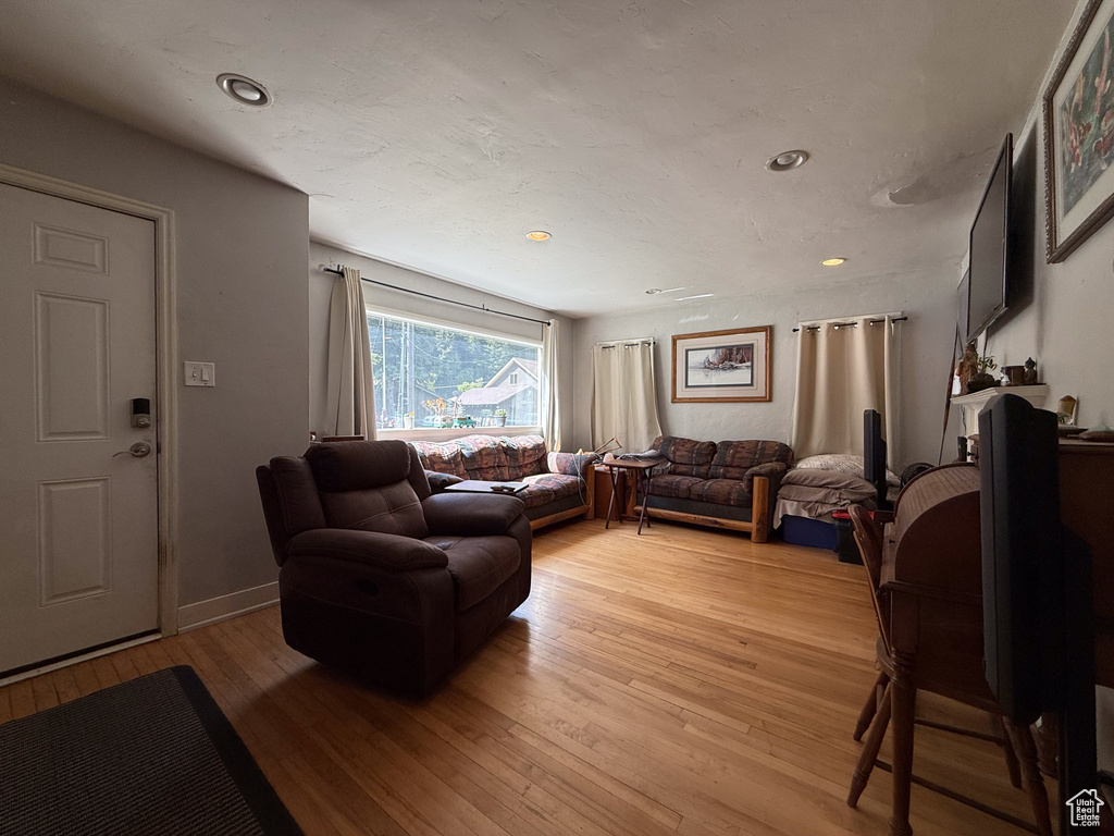 Living area with light wood-type flooring and recessed lighting