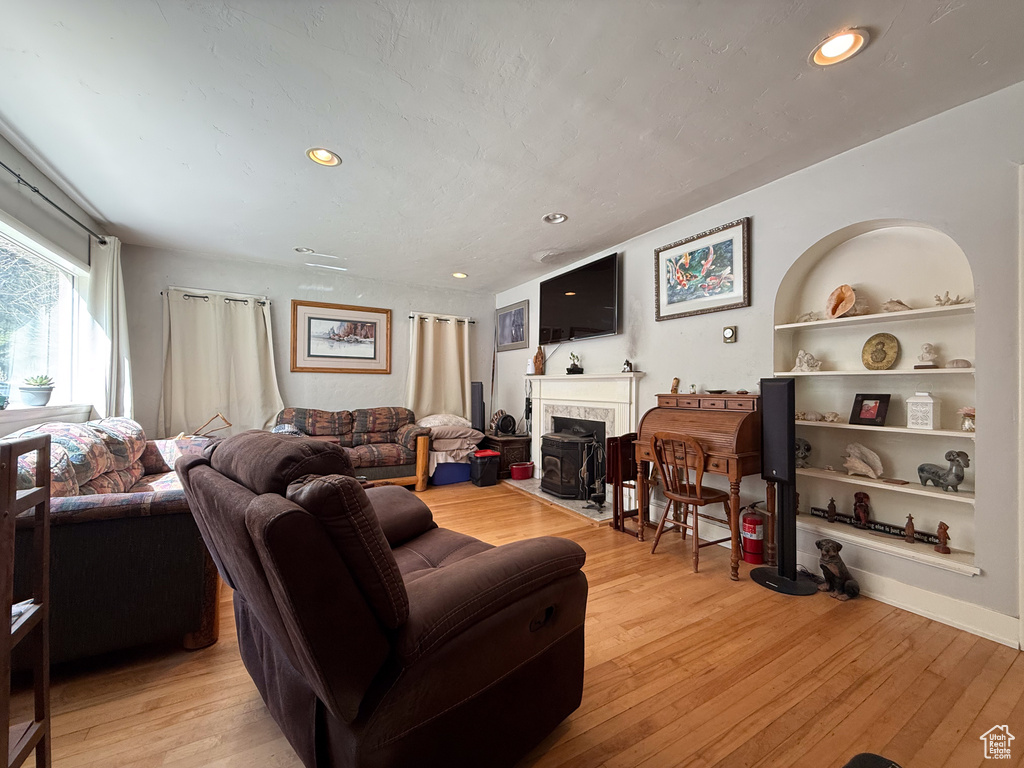 Living room with light wood finished floors, recessed lighting, a premium fireplace, and built in features