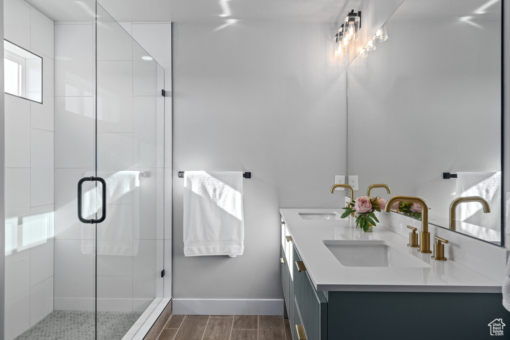 Full bath with wood tiled floors, a stall shower, double vanity, and baseboards