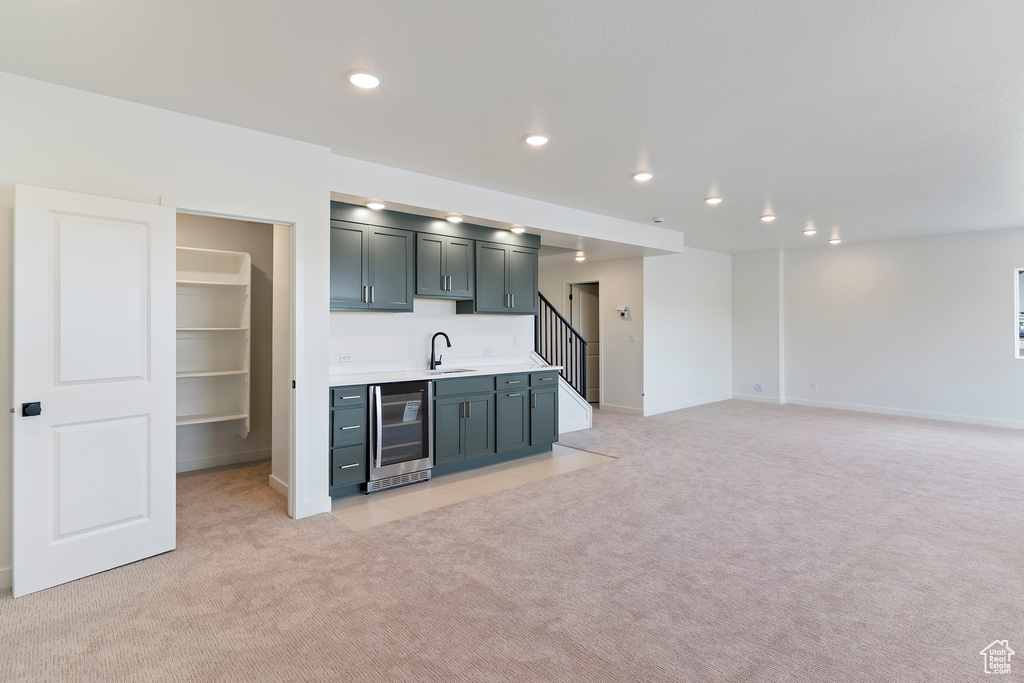 Indoor wet bar with beverage cooler, light colored carpet, baseboards, recessed lighting, and stairs