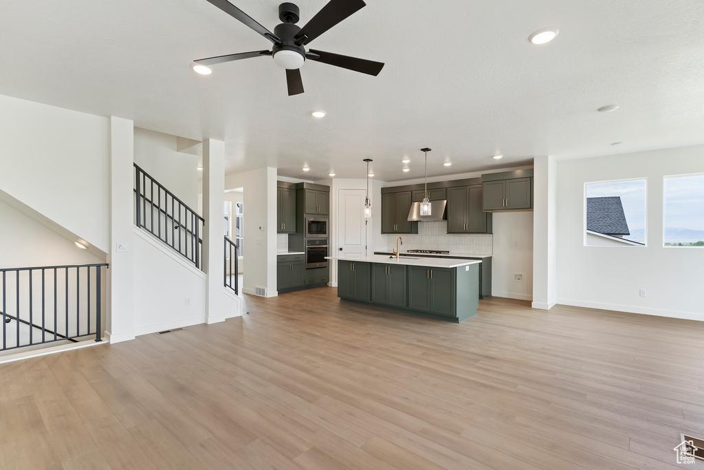 Kitchen with stainless steel appliances, a ceiling fan, open floor plan, and recessed lighting