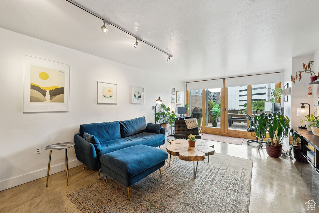 Living room with finished concrete floors, baseboards, and track lighting