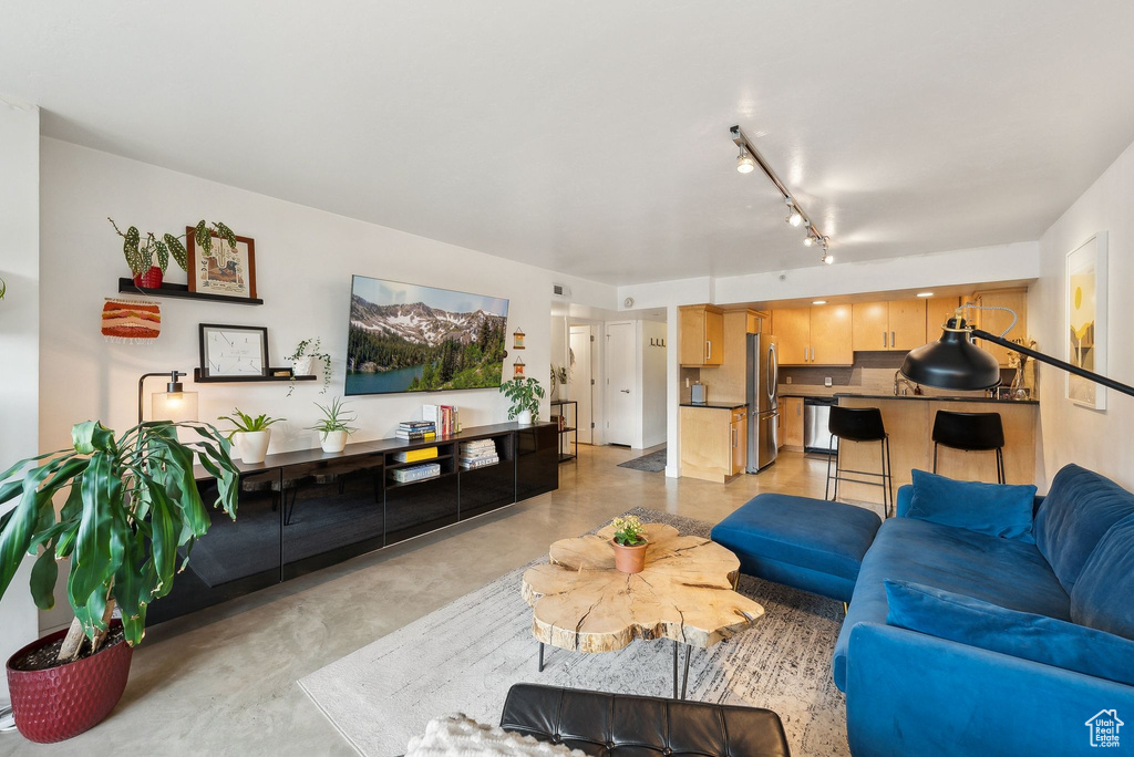 Living room with finished concrete flooring and rail lighting