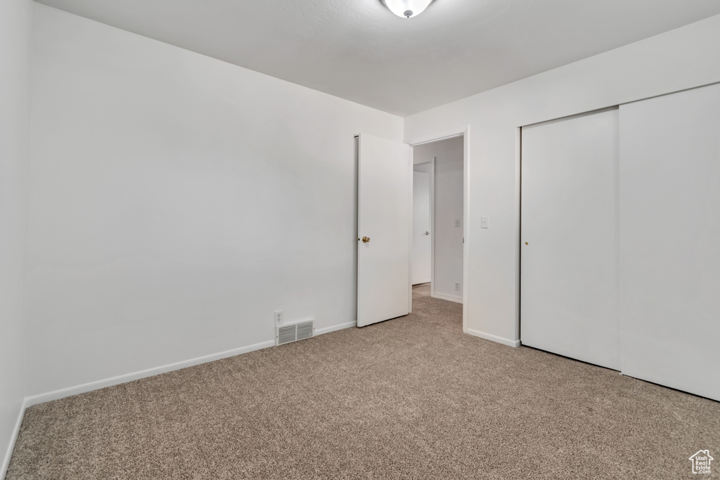 Unfurnished bedroom with carpet flooring, a closet, and baseboards