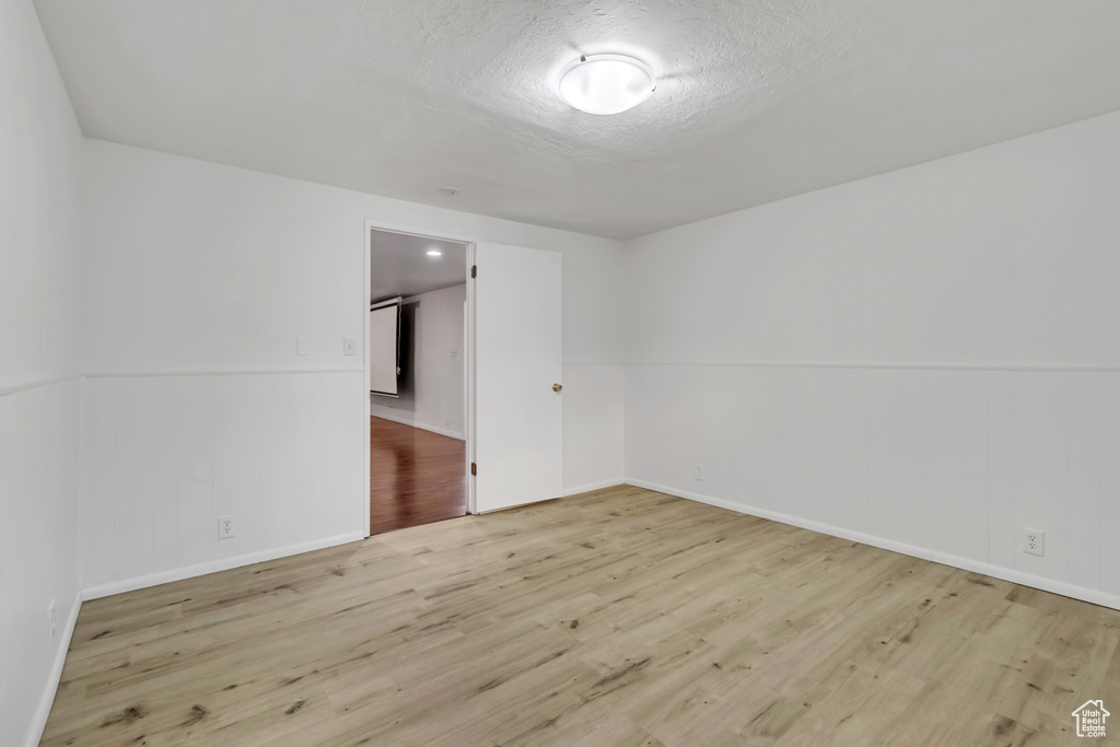 Unfurnished room with wood finished floors, baseboards, and a textured ceiling