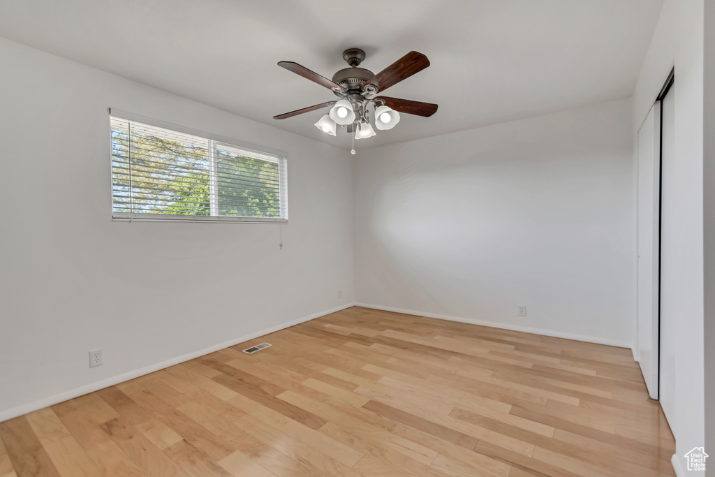 Spare room with a ceiling fan, light wood-style flooring, and baseboards