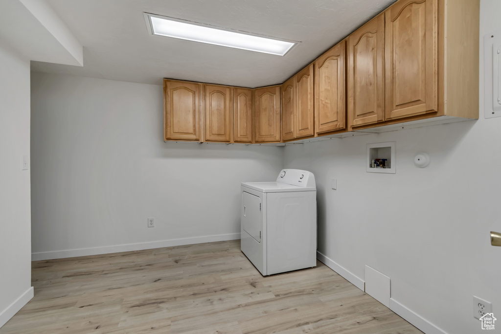 Laundry area featuring washer / clothes dryer, cabinet space, light wood finished floors, and baseboards