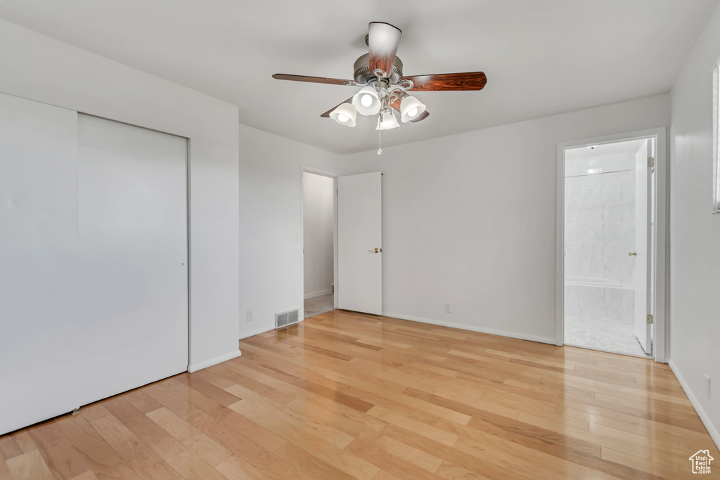 Unfurnished bedroom featuring light wood-style flooring, baseboards, ensuite bathroom, a closet, and ceiling fan