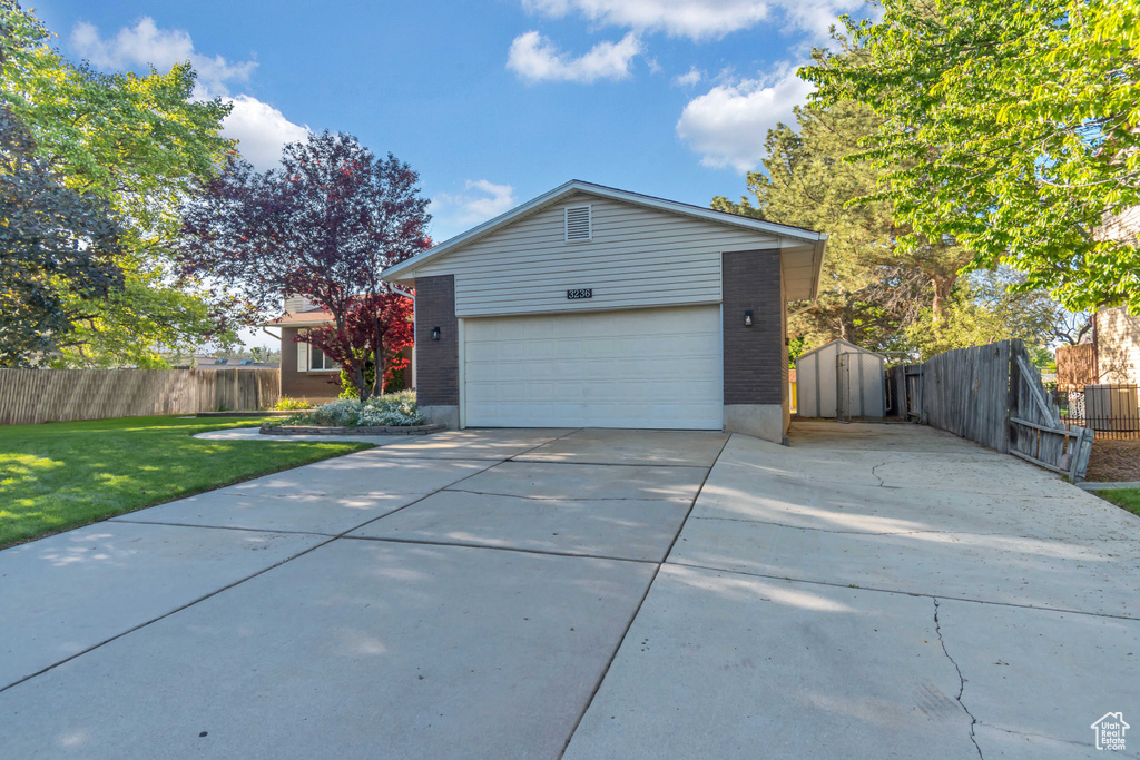 View of side of property with driveway, brick siding, and an outdoor structure
