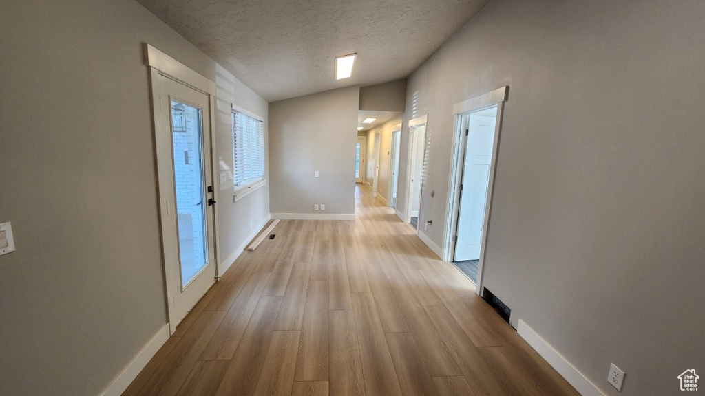 Corridor with wood finished floors, a textured ceiling, and baseboards