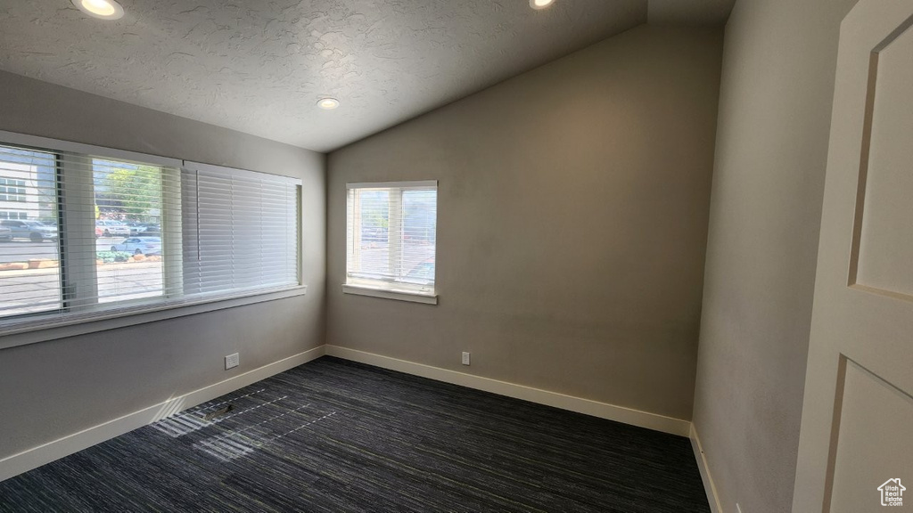 Spare room featuring vaulted ceiling, recessed lighting, baseboards, a textured ceiling, and dark colored carpet