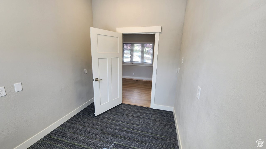 Unfurnished room featuring baseboards and dark wood-style floors