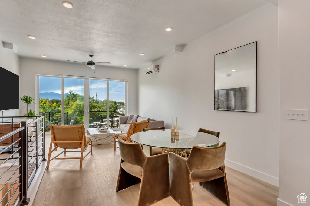 Dining space featuring a wall mounted air conditioner, light wood-style flooring, a ceiling fan, recessed lighting, and baseboards