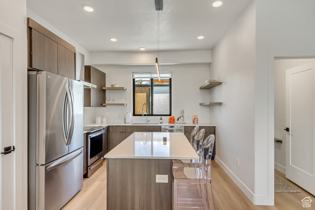 Kitchen featuring appliances with stainless steel finishes, open shelves, a sink, light wood finished floors, and modern cabinets