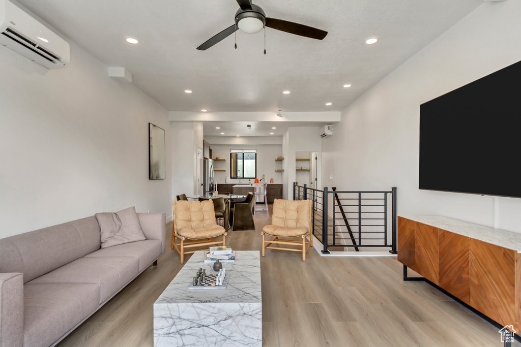 Living area featuring an AC wall unit, light wood-style floors, ceiling fan, and recessed lighting