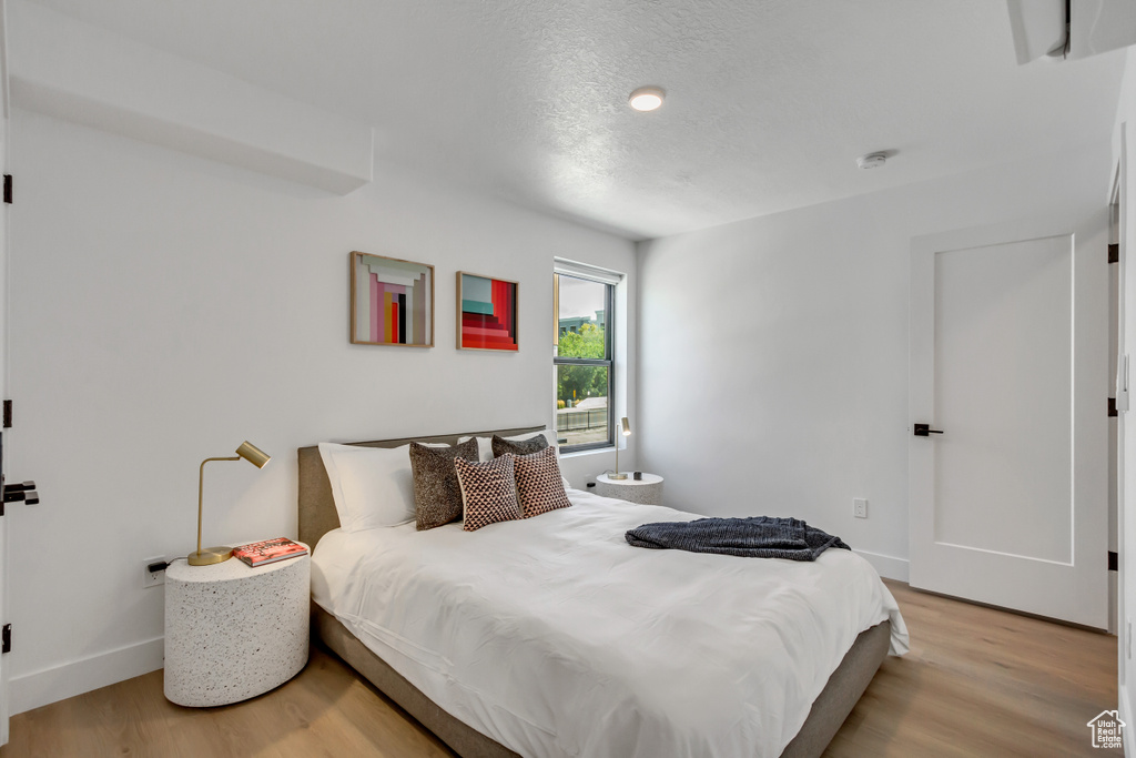 Bedroom featuring light wood-style floors, baseboards, and a textured ceiling