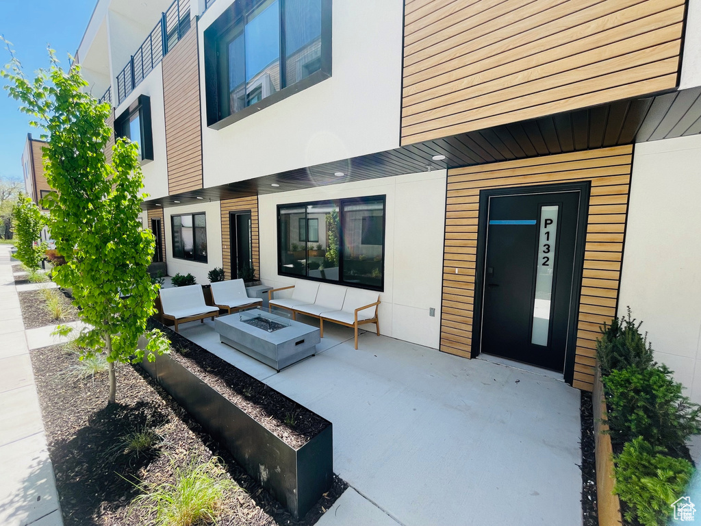 Rear view of property with an outdoor fire pit, a patio area, and stucco siding
