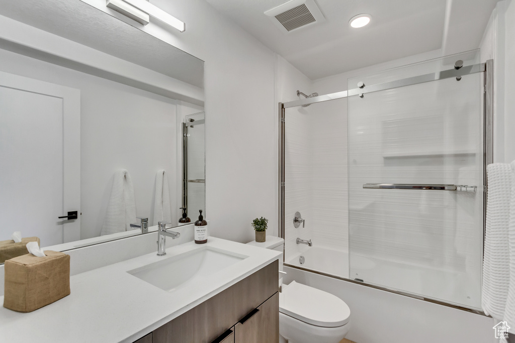 Full bath with toilet, enclosed tub / shower combo, vanity, and recessed lighting
