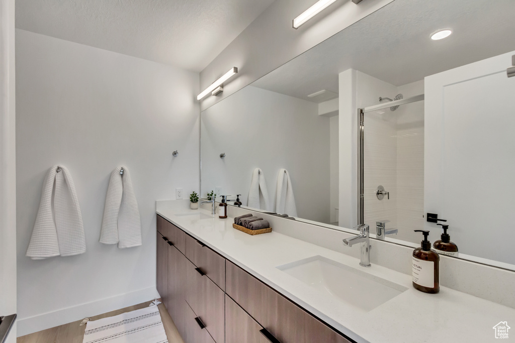 Full bath featuring a stall shower, baseboards, double vanity, and recessed lighting