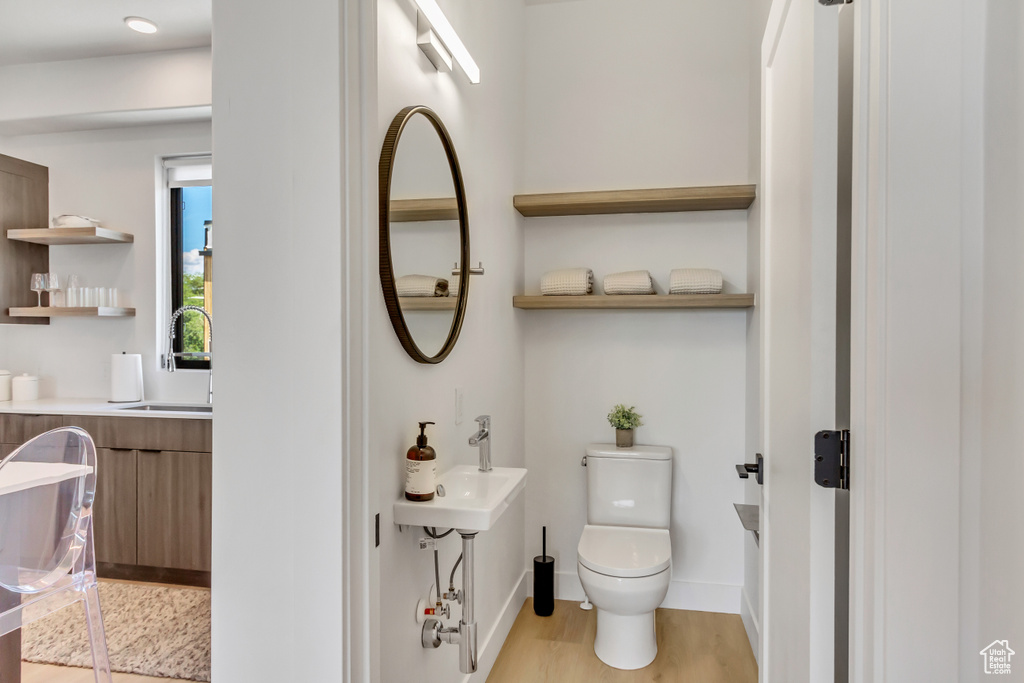 Bathroom featuring toilet, wood finished floors, baseboards, and a sink