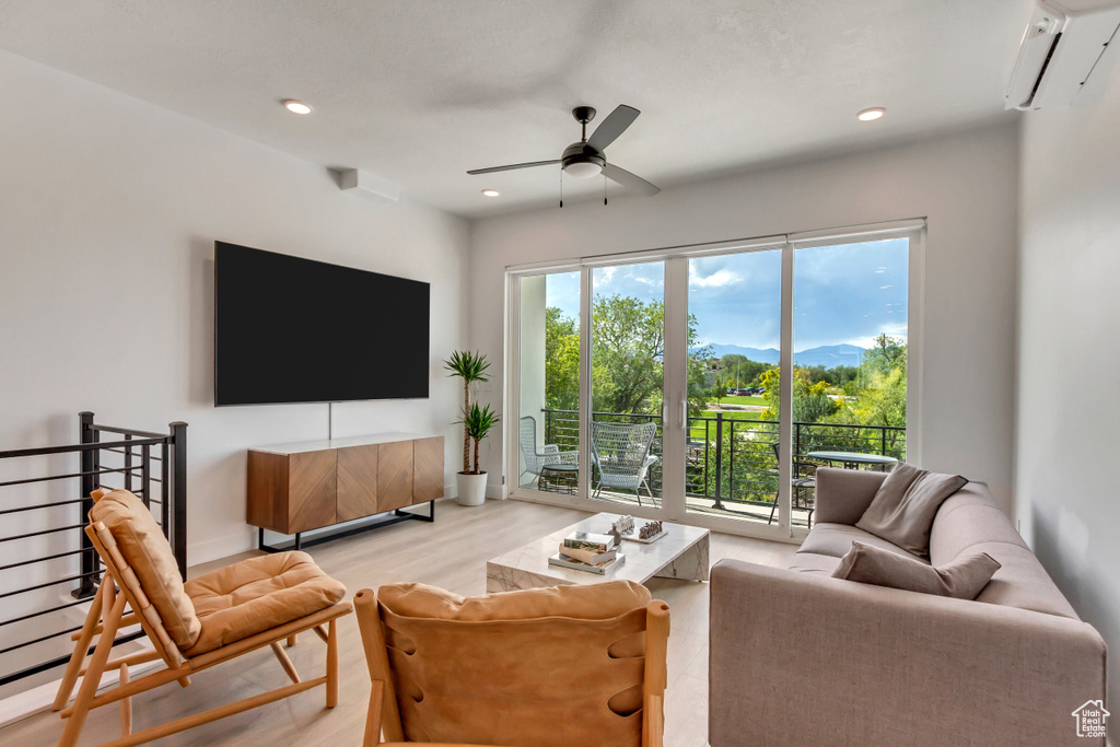 Living area with a ceiling fan, a wall mounted AC, light wood-style flooring, and recessed lighting