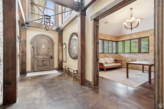 Entryway with a chandelier, finished concrete floors, high vaulted ceiling, and baseboards