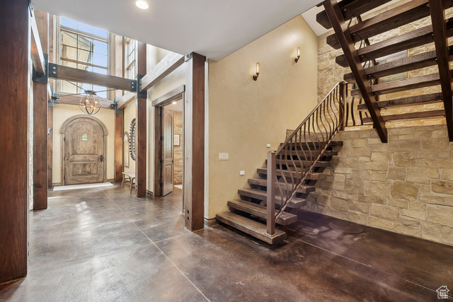 Stairs featuring concrete floors, arched walkways, and a chandelier