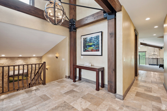 Corridor featuring stone tile flooring, a chandelier, baseboards, an upstairs landing, and recessed lighting