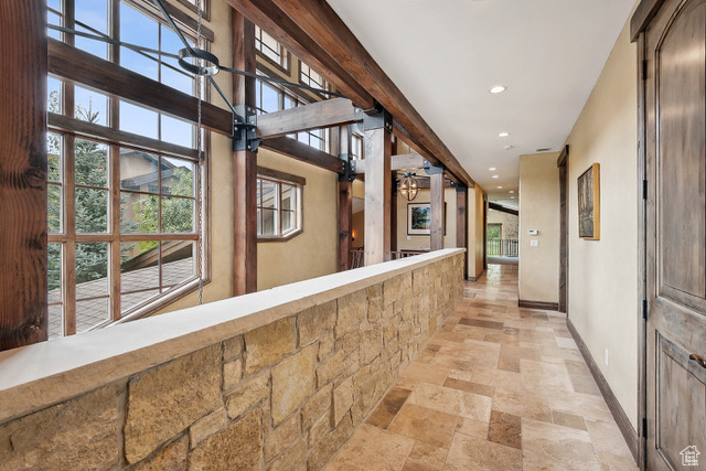 Corridor featuring stone tile flooring, baseboards, recessed lighting, and healthy amount of natural light