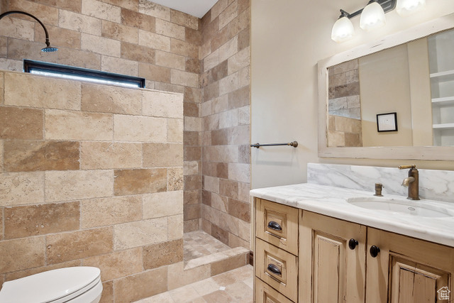 Bathroom with tiled shower, vanity, and toilet