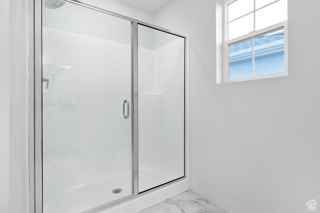 Full bathroom featuring a stall shower, baseboards, and marble finish flooring