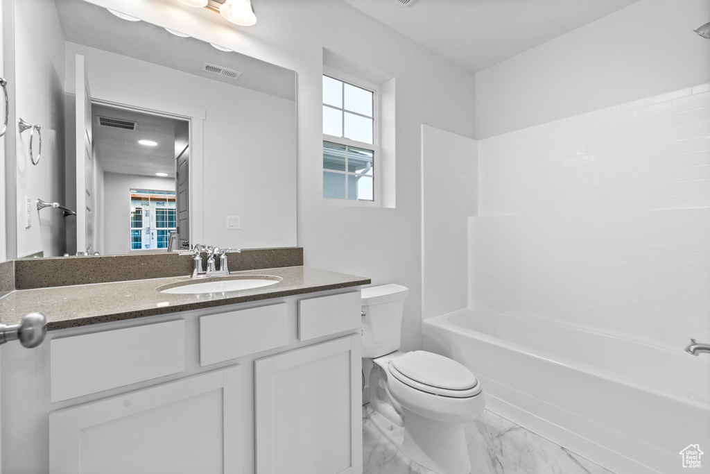 Bathroom with toilet, marble finish floors, vanity, and  shower combination