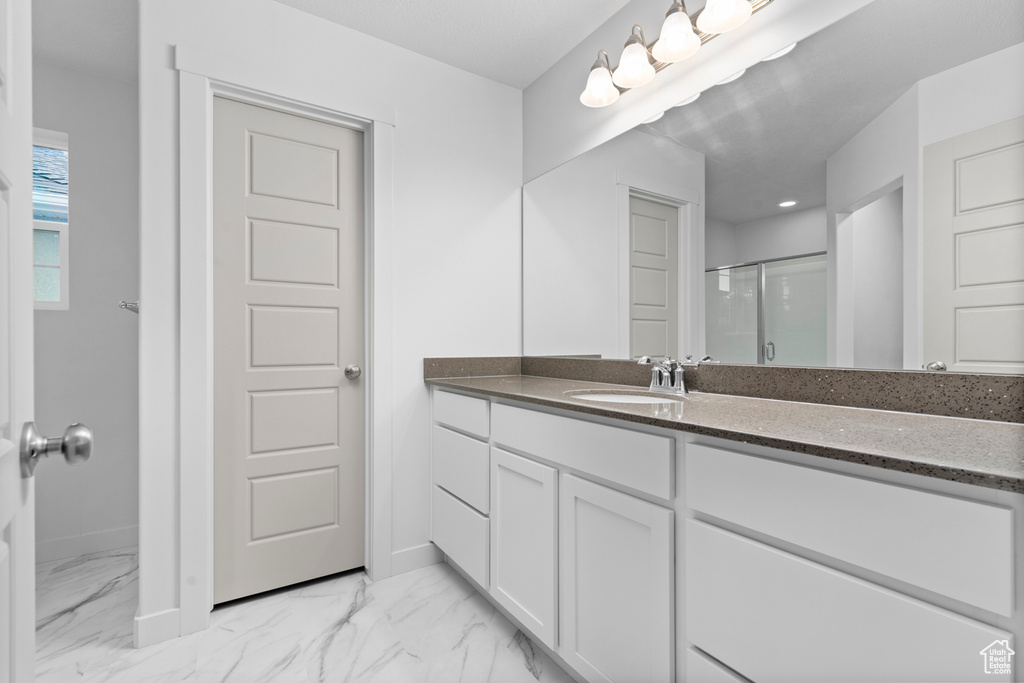 Bathroom with a stall shower, marble look tile flooring, vanity, and baseboards