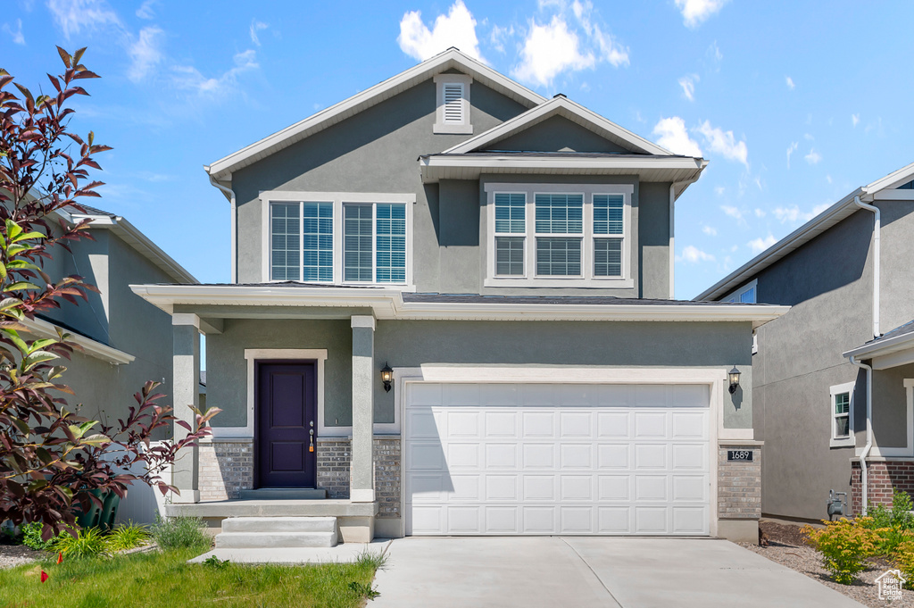 View of front of home featuring stucco siding, a garage, and driveway
