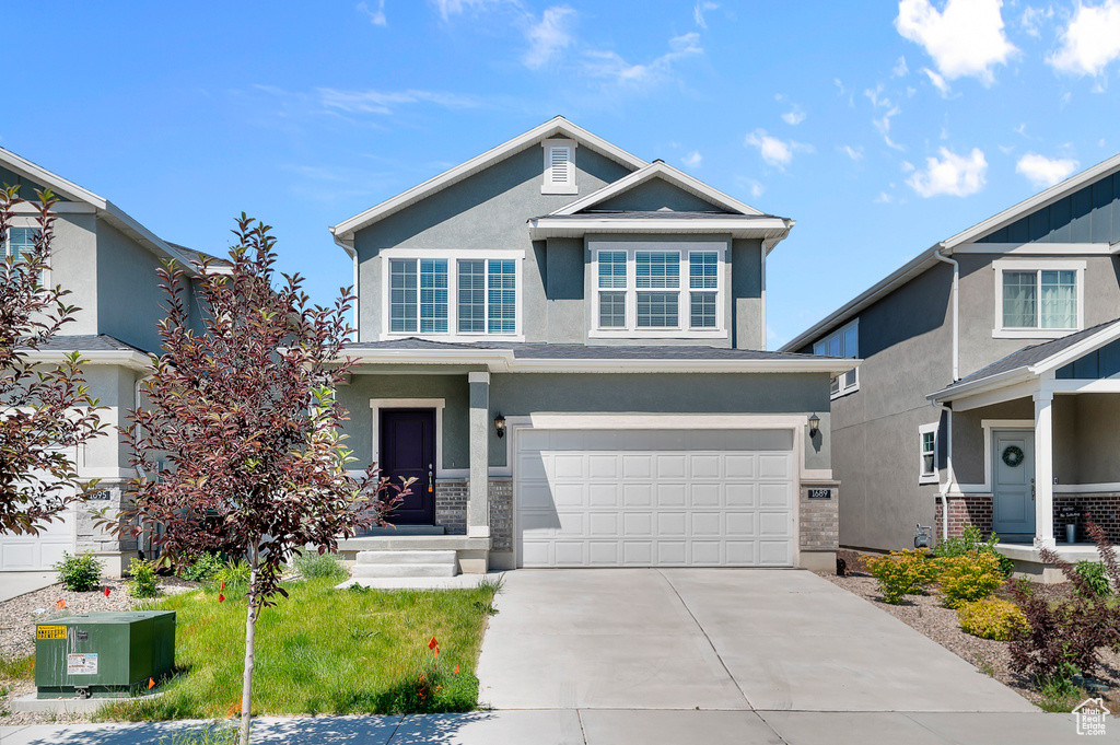 View of front of home with an attached garage, stucco siding, and driveway
