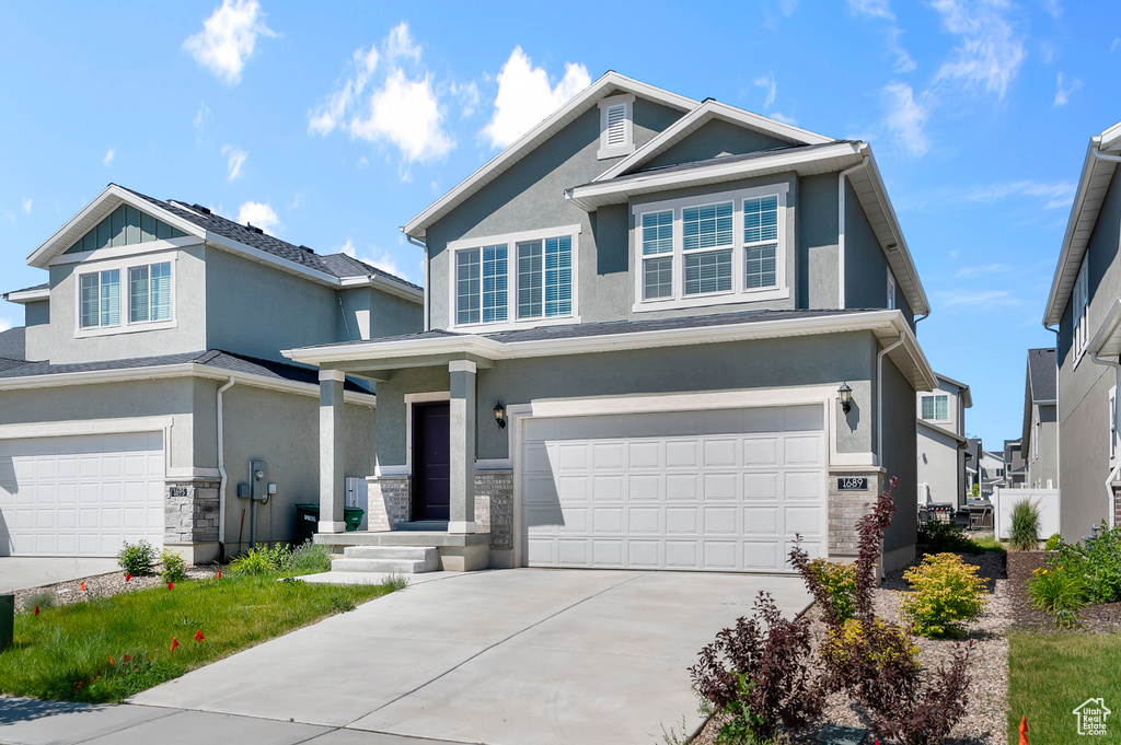 View of front facade with an attached garage, stucco siding, concrete driveway, and stone siding