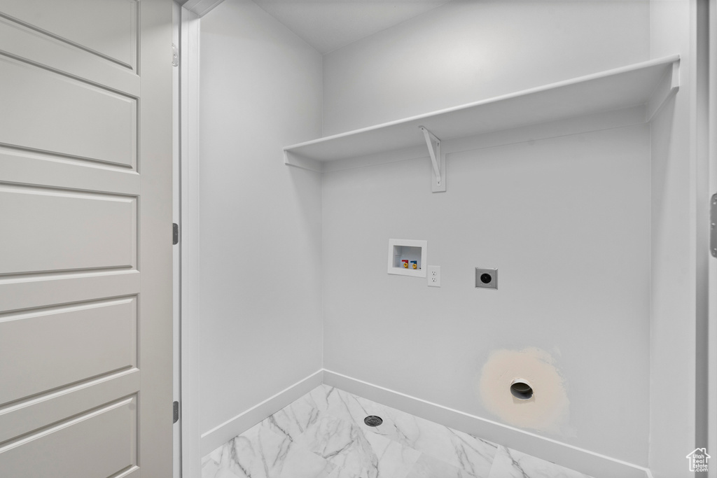 Washroom with electric dryer hookup, washer hookup, marble finish flooring, and baseboards