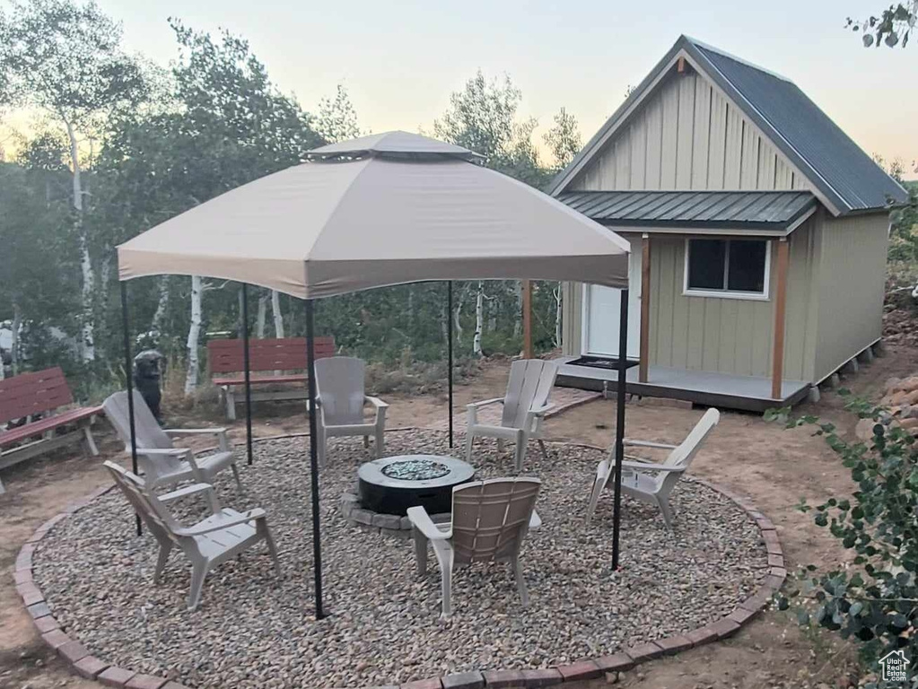 Back of house with an outdoor fire pit, board and batten siding, an outbuilding, and a gazebo