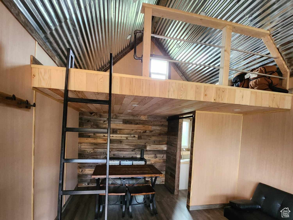 Misc room featuring wooden walls, wood finished floors, and high vaulted ceiling