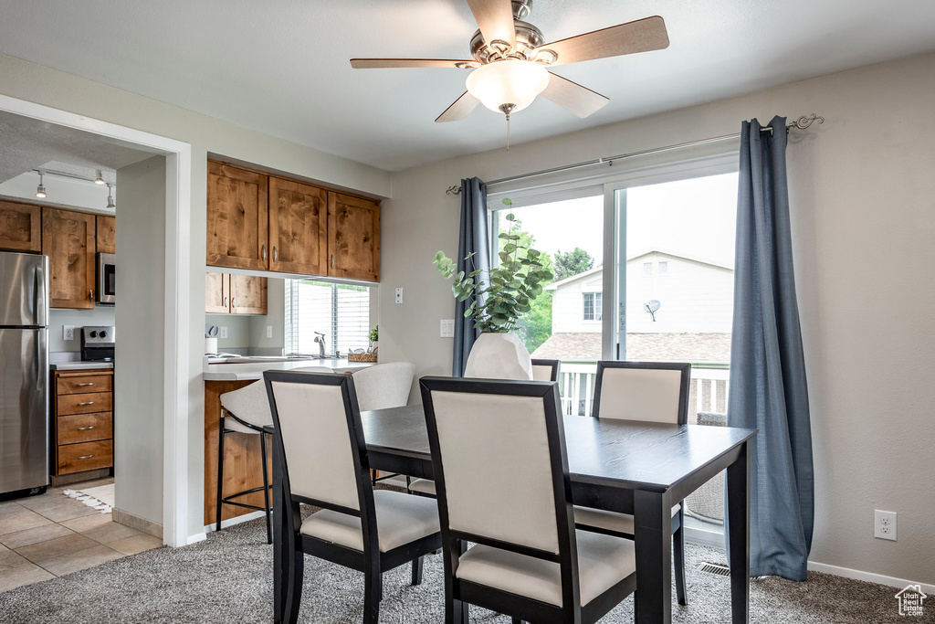 Dining area with ceiling fan, baseboards, and light carpet