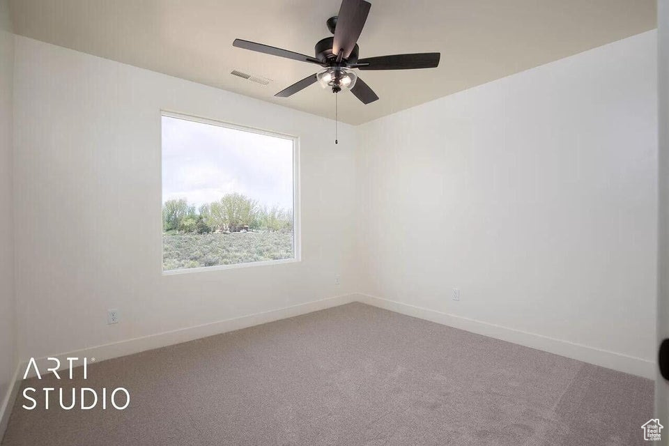 Carpeted empty room with baseboards and a ceiling fan