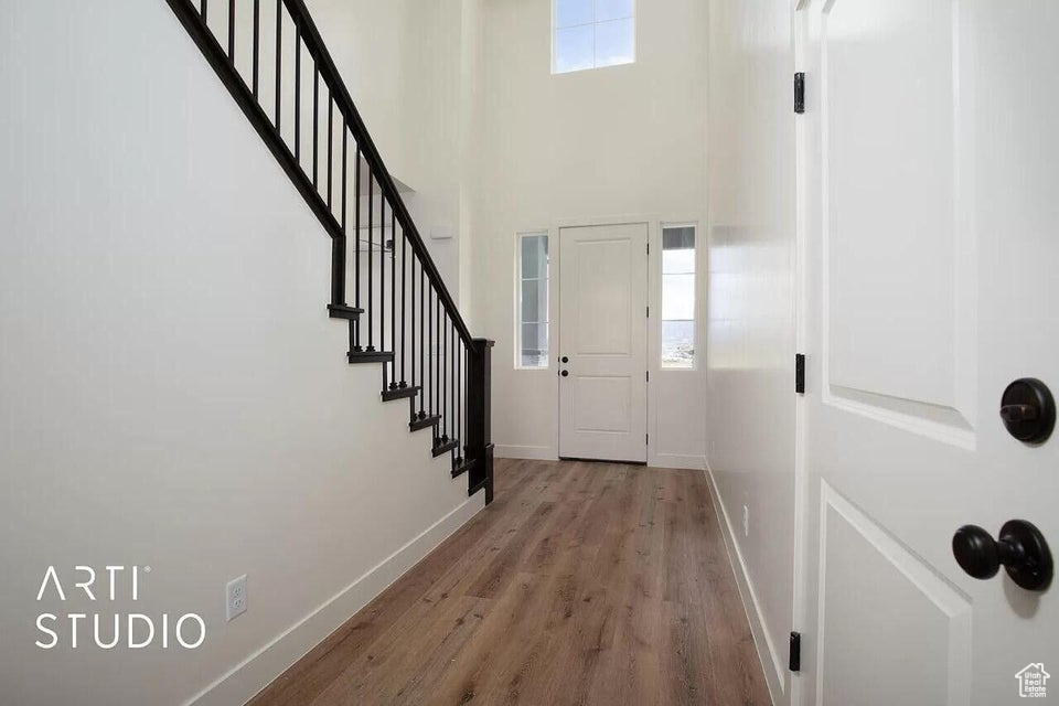 Foyer entrance with wood finished floors, baseboards, stairs, and a high ceiling