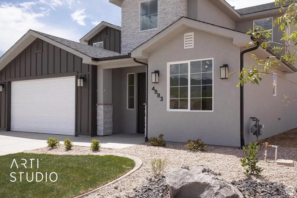 View of front of house featuring a garage, board and batten siding, driveway, and stucco siding